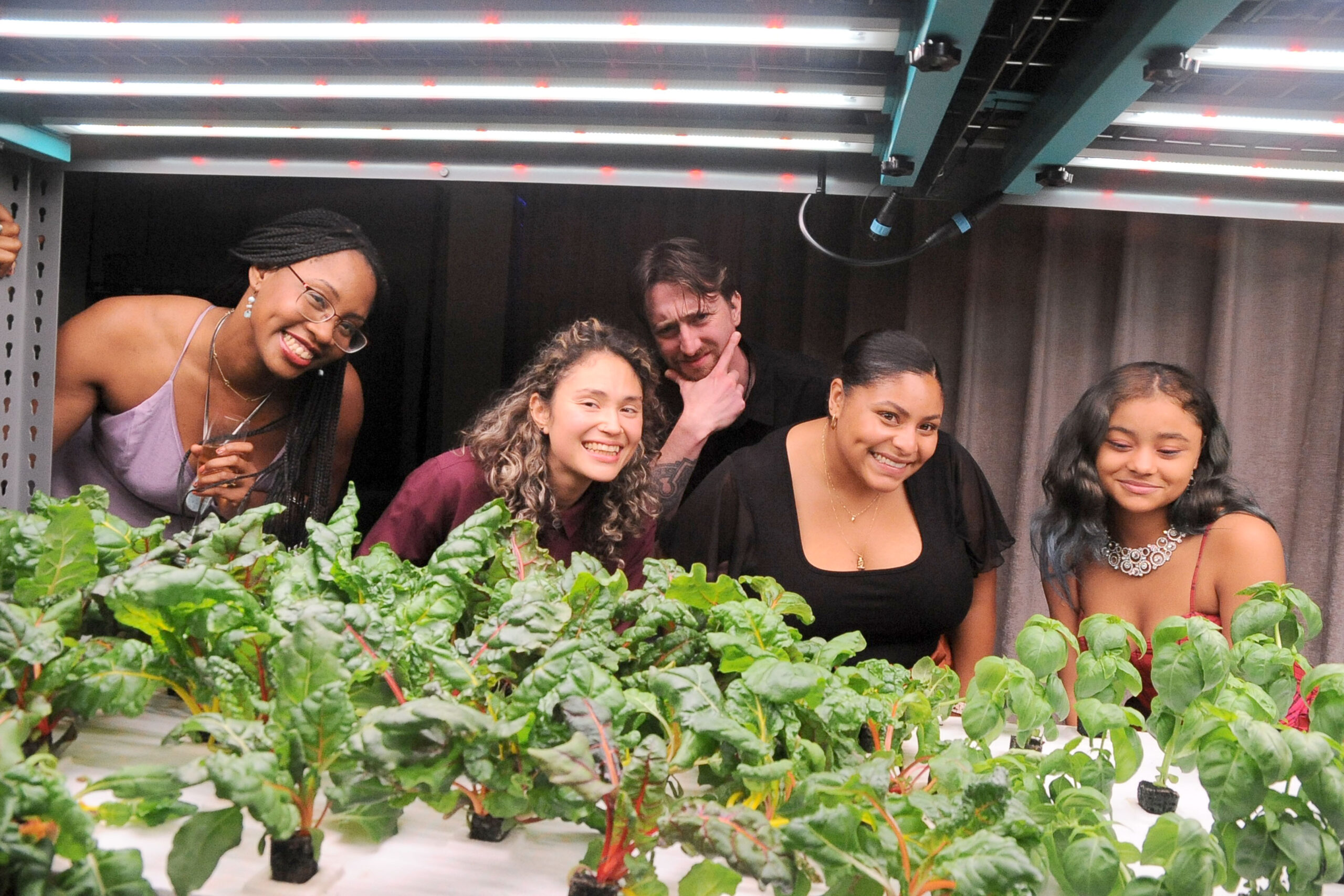 Friends and colleagues pose behind hydroponic system at TFFJ Feast 2023 Gala.